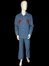 Load image into Gallery viewer, A blue denim two-piece set consisting of a long-sleeve button-front shirt and matching pants, displayed on a white mannequin. The shirt features colorful embroidered patterns on the chest in red, orange, and yellow.
