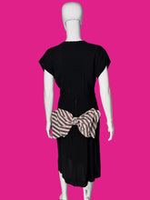 Load image into Gallery viewer, A back view of a black short-sleeve dress shown on a white mannequin, featuring a pink and white striped waist sash with a large bow at the back waist.