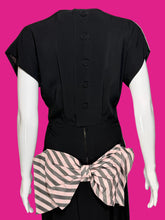 Load image into Gallery viewer, Black short-sleeve dress shown from the back on a white mannequin, featuring a row of black buttons down the center back and a large pink and gray striped bow at the waist.