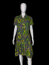 Load image into Gallery viewer, A short-sleeve collared dress with a vibrant green, yellow, purple, and blue paisley pattern, displayed on a white mannequin against a plain wall.