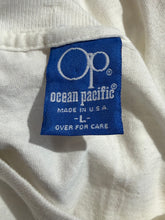 Load image into Gallery viewer, A close-up of a white fabric garment showing a blue woven label with white text reading Ocean Pacific and size L.