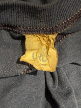 Load image into Gallery viewer, Close-up of a dark gray knit garment showing a yellow fabric brand tag sewn inside the neckline. The tag has a blue anchor logo.