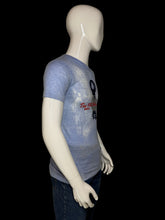 Load image into Gallery viewer, A mannequin wearing a faded light blue graphic t-shirt.