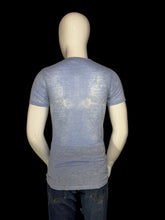 Load image into Gallery viewer, A mannequin wearing a faded light blue graphic t-shirt from a back view.