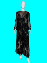 Load image into Gallery viewer, A black sheer maxi dress with a metallic gold abstract pattern, displayed on a white mannequin.
