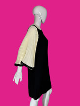 Load image into Gallery viewer, A black dress displayed on a white mannequin, featuring three-quarter pleated cream sleeves with black trim.
