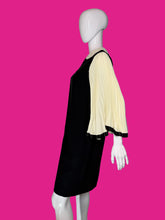 Load image into Gallery viewer, A black dress displayed on a white mannequin, featuring three-quarter pleated cream sleeves with black trim.