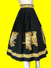 Load image into Gallery viewer, A black pleated A-line skirt with a leopard print pattern and gold floral borders, displayed on a white mannequin.