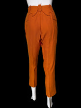 Load image into Gallery viewer, Bright orange cropped trousers with decorative curved welt pockets and a unique front closure, displayed on a white mannequin.
