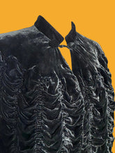 Load image into Gallery viewer, Close up of a black textured cape jacket with a scalloped ruffled edge and high collar, shown on a white mannequin.