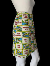 Load image into Gallery viewer, A high-waisted, pleated mini skirt featuring a colorful patchwork print of vintage comic book panels with text like 'PLEASE BE SEATED' and 'THAT'S ALL FOLKS!'.