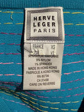 Load image into Gallery viewer, Close-up of a sewn-in clothing label reading HERVE LEGER PARIS, attached to a turquoise knit garment with multicolored stitching.