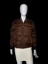 Load image into Gallery viewer, A brown quilted bomber jacket with gold-colored piping and a dark brown ribbed collar, cuffs, and hem, displayed on a white mannequin.