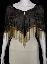 Load image into Gallery viewer, A close up of a black mesh shawl with gold sequins and fringe trim, displayed on a white mannequin torso highlighting the delicate gold threading.