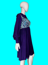 Load image into Gallery viewer, A long sleeve blue mini dress with a light blue and silver psychadelic print on the bodice and a dramatic collar shown from the side on a white mannequin.