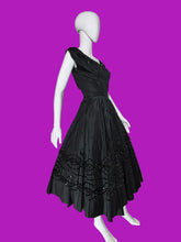 Load image into Gallery viewer, A black sleeveless fit-and-flare dress with cap sleeves, a scoop neckline, and ornate lace and bead trim details, displayed on a white mannequin.