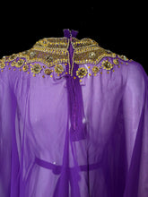 Load image into Gallery viewer, A purple sheer tunic with elaborate gold beaded and sequined embellishments around the high neckline, displayed on a white mannequin torso.