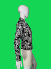 Load image into Gallery viewer, A long-sleeve button-up blouse with a black and white spiral swirl pattern, displayed on a white mannequin torso shown from the side.