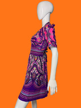Load image into Gallery viewer, A side view of a purple and pink paisley print short-sleeve dress displayed on a white mannequin.