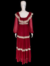 Load image into Gallery viewer, A long maroon chiffon and lace prairie dress displayed on a white mannequin from the back, featuring sheer long sleeves, a square neckline with cream lace trim, and matching lace bands at the waist and hem.