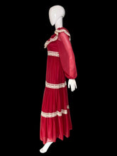 Load image into Gallery viewer, A long maroon chiffon and lace prairie dress displayed on a white mannequin from the side, featuring sheer long sleeves, a square neckline with cream lace trim, and matching lace bands at the waist and hem.