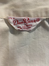 Load image into Gallery viewer, Close-up of a cream-colored cotton fabric garment showing the interior neck label which reads 'Dan River FABRIC ALL COTTON' in red text.