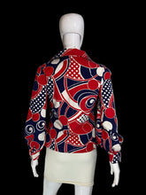 Load image into Gallery viewer, A long-sleeve button-up shirt with a bold abstract geometric pattern in red, navy blue, and white, displayed on a white mannequin torso.