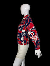 Load image into Gallery viewer, A long-sleeve button-up shirt with a bold abstract geometric pattern in red, navy blue, and white, displayed on a white mannequin torso.