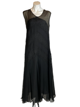 Load image into Gallery viewer, A sleeveless black dress with sheer mesh shoulder panels and lace applique, displayed on a mannequin against a plain white background.