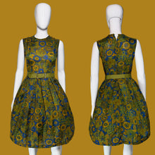 Load image into Gallery viewer, A sleeveless fit-and-flare dress with a pleated skirt and matching belt, shown from the front and back on a white mannequin. The dress features a bold mid-century floral pattern in olive green, mustard yellow, and blue.
