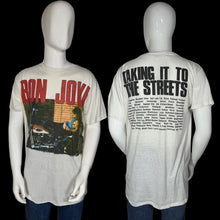 Load image into Gallery viewer, A vintage-style Bon Jovi graphic T-shirt shown on a white mannequin from both front and back views. The front features red 'BON JOVI' text over a multicolor graphic print, and the back displays large black 'TAKING IT TO THE STREETS' text above a block of small black text.
