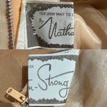 Load image into Gallery viewer, Close-up of a label on a beige fabric background.
