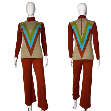 Mannequin wearing a vintage outfit with a red sweater and pants and a beige vest with colorful V-pattern on a white background.