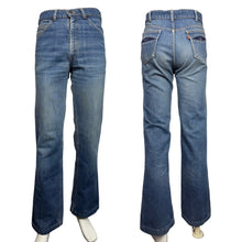 Load image into Gallery viewer, Pair of blue jeans displayed from front and back on mannequins against a white wall.
