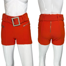 Load image into Gallery viewer, Orange shorts with a belt and silver buckle on white mannequins.
