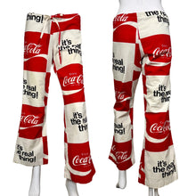 Load image into Gallery viewer, Red and white Coca-Cola themed pants displayed on mannequins against a neutral background.
