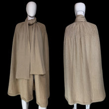 Load image into Gallery viewer, A beige ribbed knit cape with a draped collar and layered hem, displayed on a white mannequin.

