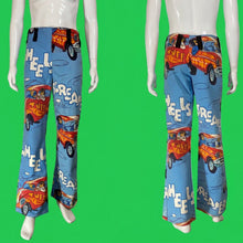 Load image into Gallery viewer, A pair of wide-leg pants displayed on a mannequin from the front and back. The pants feature a bright blue background with a retro-style print of orange and red hot rods, white text reading 'WHEELS ARE GREAT', and cartoon characters.
