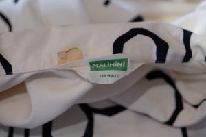 Close-up of a Malihini Hawaii label on a garment with black geometric patterns.
