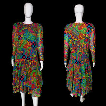 Load image into Gallery viewer, A long-sleeve tiered dress displayed on a white mannequin from both the front and back views, featuring a highly vibrant, multicolored psychedelic abstract pattern with swirls, paisley, and checkerboard motifs.
