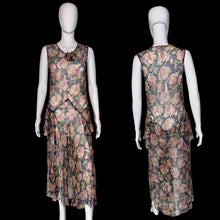 Load image into Gallery viewer, A sleeveless dress with a floral print, shown from both the front and back on a white mannequin. The dress features a navy blue base with pink, red, and green floral patterns, and a ruffled asymmetrical hem.
