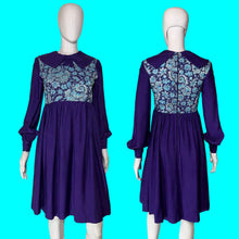 Load image into Gallery viewer, A long sleeve blue mini dress with a light blue and silver psychadelic print on the bodice and a dramatic collar shown from the front and back on a white mannequin.
