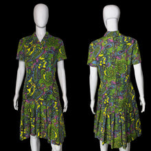 Load image into Gallery viewer, A side-by-side front and back view of a short-sleeve collared dress with a vibrant green, yellow, purple, and blue paisley pattern, displayed on a white mannequin against a plain wall.
