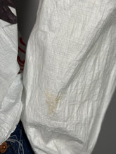 Load image into Gallery viewer, Close-up of a white fabric with a brown stain on a dark background
