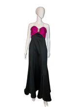 Load image into Gallery viewer, Mannequin wearing a black dress with a pink bow on a white platform.
