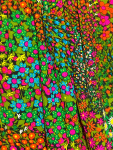 Colorful floral dress on a mannequin against a plain wall.