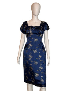 Navy blue dress with white floral pattern on a mannequin against a beige wall.