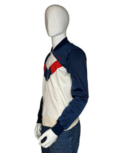 Mannequin wearing a navy jacket with red and white accents on a plain background