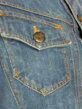 Load image into Gallery viewer, Close-up of a blue denim jacket with a button and stitching details.
