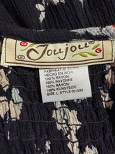 Load image into Gallery viewer, Close-up of a Joujou label on a patterned fabric background
